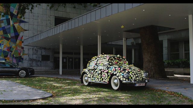 Video Reference: vintage car, art installation, sticky notes, outdoor, modern building, parking, street art, colorful, vehicle, architecture, entrance, tree, urban, exterior, museum, public art