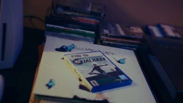 Video Reference: video game, PS5, game case, console, stack, magazines, indoor, close-up, entertainment, media, collection, table, blurred background