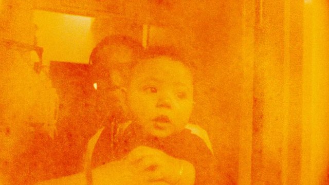 Video Reference: child, adult, indoor, close-up, orange tint, low light, blurry, home, portrait, family, unclear