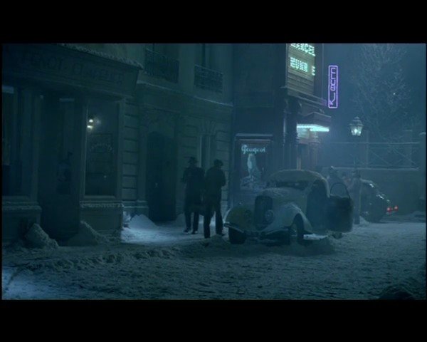 Video Reference: snow, night, street, vintage car, parked cars, people walking, building exterior, neon sign, winter, urban, foggy, cold, sidewalk, city