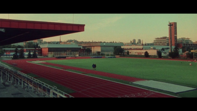 Video Reference: Sky, Rectangle, Building, Flooring, Grass, Race track, Urban design, Asphalt, Tints and shades, City