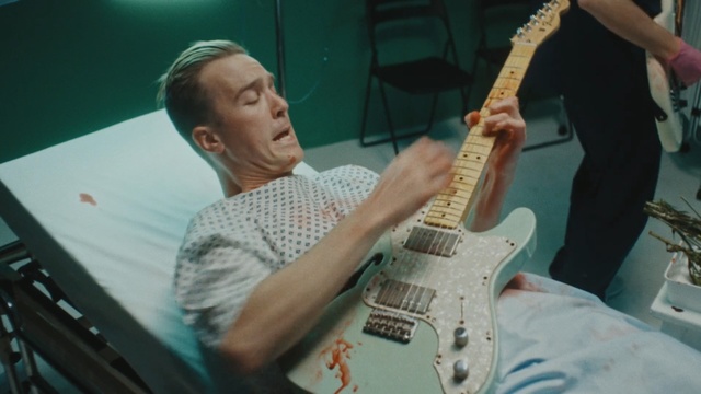Video Reference: Guitar, String instrument, Musical instrument, Musician, Guitarist, Plucked string instruments, Music, Bass guitar, Electric guitar, Person, Man, Indoor, Holding, Table, Sitting, Cutting, Young, Cake, Blue, Standing, Board, Knife, Playing, White, Game, Baseball, Pizza, Plate, Concert, Bass