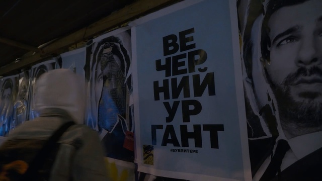 Video Reference: Text, Font, Poster, Art, Advertising, Person, Indoor, Sitting, Man, Young, Woman, White, Holding, Room, People, Bed, Standing, Sign