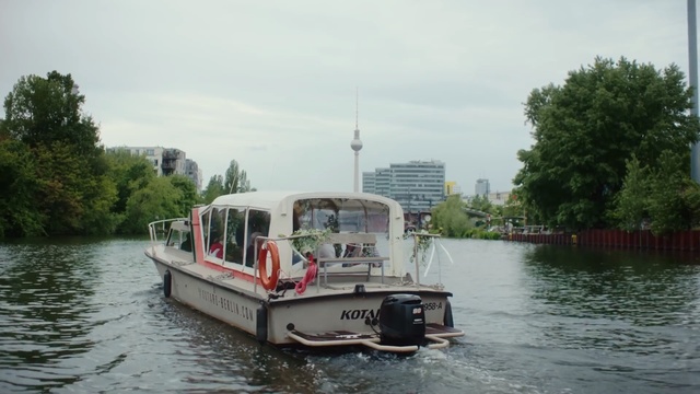 Video Reference: Vehicle, Water transportation, Waterway, Boat, Canal, Watercraft, Transport, Ferry, Channel, Tugboat, Water, Outdoor, River, Small, Body, Lake, White, Traveling, Large, Floating, Docked, Dock, Man, Driving, Old, Bridge, Riding, City, People, Parked, Tree, Sky, Ship, Travel