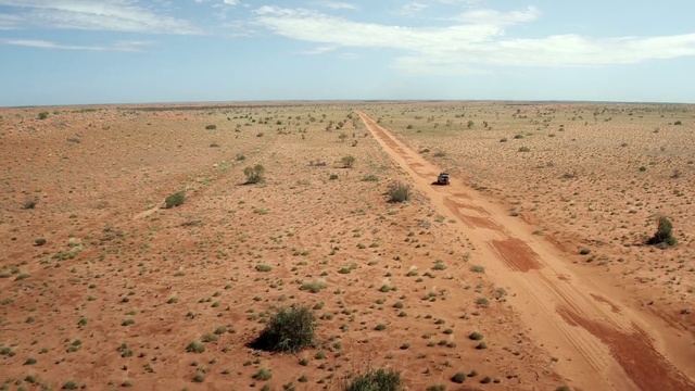 Video Reference: Desert, Natural environment, Sand, Ecoregion, Sahara, Soil, Aeolian landform, Landscape, Sky, Plain, Outdoor, Beach, Nature, Water, Sandy, Ocean, Walking, Man, People, Group, Dirt, Standing, Board, Herd, Riding, Giraffe, Ground, Cloud, Shore, Dune