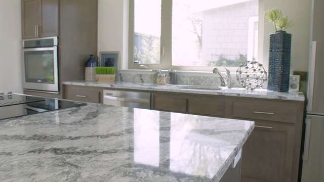 Video Reference: countertop, kitchen, room, floor, sink, tile, furniture, granite, flooring, cabinetry, Person