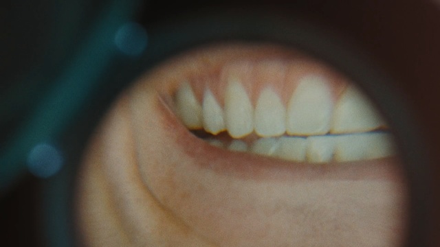 Video Reference: Tooth, Jaw, Facial expression, Mouth, Skin, Organ, Smile, Close-up, Nose, Lip, Indoor, Sitting, Looking, Cat, Close, Orange, Brown, Red, Banana, Small, Face, Television, Monitor, Food, Black, Table, White, Blue, Eyes, Closeup, Eyelash, Cosmetics, Domestic cat