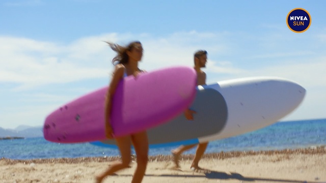 Video Reference: Surfboard, Surfing equipment, Sand, Pink, Inflatable, Surfing, Games, Summer, Fun, Beach, Outdoor, Water, Holding, Woman, Walking, Girl, Ocean, Board, Standing, Man, Carrying, Red, Blue, Wave, White, Frisbee, Sky, Shore