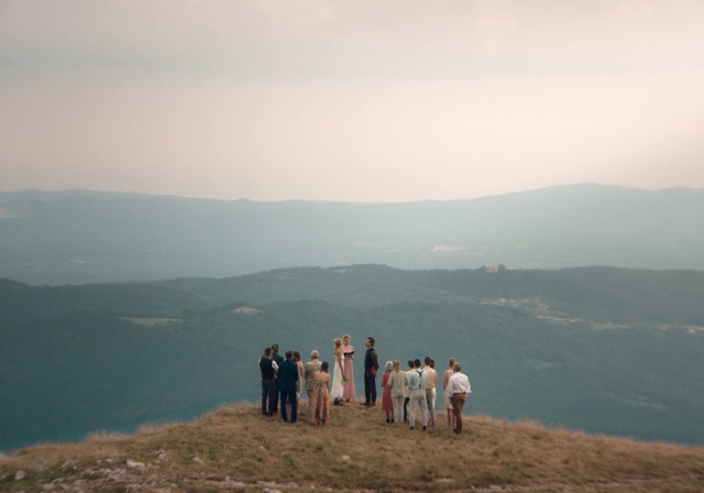 Video Reference: Sky, Hill station, Mountainous landforms, Atmospheric phenomenon, Mountain, Hill, Highland, Wilderness, Horizon, Cloud, Outdoor, Nature, Water, Grass, Standing, Group, Field, Beach, Horse, Man, Cow, Large, River, People, Lake, Walking, Herd, Grazing, Cattle, Body, Ocean, Fog, Person, Hiking, Summer, Promontory