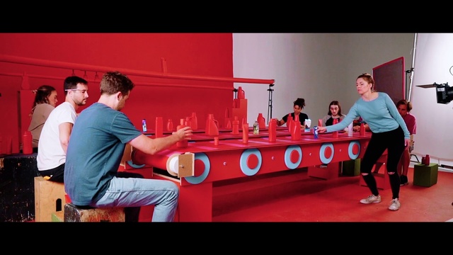 Video Reference: Room, Team, Games, Person, Man, Indoor, Red, Playing, Court, Holding, Standing, Table, Woman, Game, Video, Ball, Player, Young, People, Swinging, White, Group, Clothing, Human face