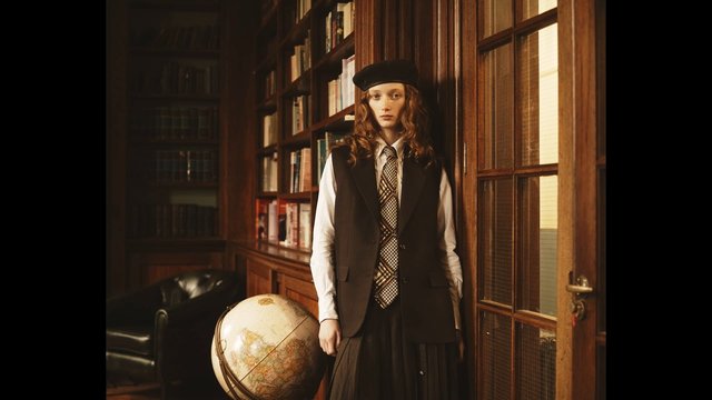 Video Reference: library, bookshelves, globe, woman, beret, tie, wood paneling, indoor, warm light, standing, books, door, vintage, formal attire