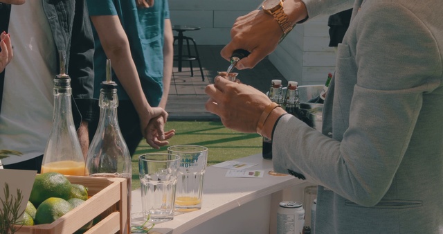 Video Reference: Hand, Science, Laboratory, Chemistry, Person, Indoor, Woman, Table, Man, Food, Standing, Holding, Preparing, Front, People, Wine, Cake, Kitchen, Cutting, Plate, Young, Sandwich, Meat, Group, Bottle, Watch