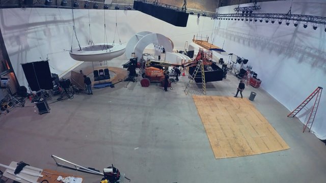 Video Reference: film set, soundstage, studio, production, lighting rig, ladder, equipment, crew, white cyclorama, construction, set design, indoor, platform, vfx stage, behind the scenes