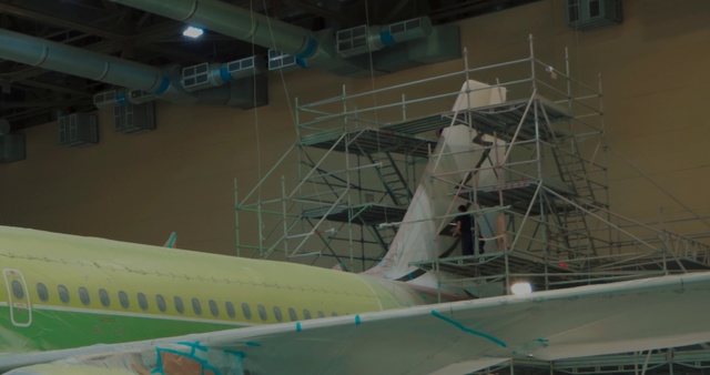 Video Reference: Airplane, Aerospace engineering, Scale model, Aircraft, Aviation, Vehicle, Airliner, Wing, Flap, Narrow-body aircraft, Plane, Green, Airport, Sitting, Large, Parked, Passenger, Air, White, Small, Jet, Commercial, Table, Luggage, Yellow, Blue, Tarmac, Docked, Runway