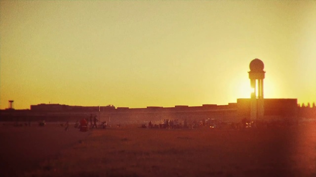 Video Reference: Sky, Atmospheric phenomenon, Horizon, Morning, Orange, Sunrise, Sunset, Ecoregion, Evening, Heat, Outdoor, Sun, Building, Yellow, Large, Clouds, Walking, Plane, Light, Track, Standing, Water, Flying, Field, Airplane, Red, Man, Beach, Jet, City, Tower, Runway, Kite, Ocean, Cloud, Desert, Distance, Day