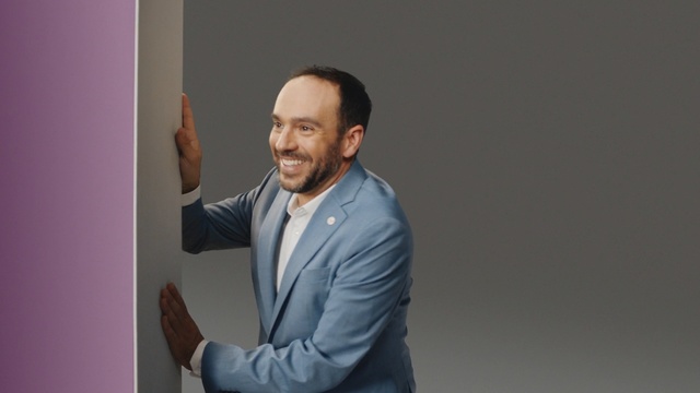 Video Reference: Businessperson, Gesture, White-collar worker, Suit, Business, Person, Man, Indoor, Standing, Holding, Front, Looking, Hand, Shirt, Monitor, Wearing, Remote, Video, Young, Playing, Room, Television, Game, Wii, Wall, Human face, Clothing, Smile, Tie