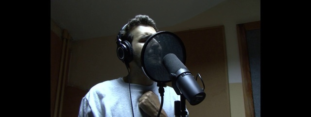 Video Reference: Audio equipment, Personal protective equipment, Microphone, Headgear, Technology, Gas mask, Electronic device, Hearing, Costume, Indoor, Person, Man, Front, Sitting, Holding, Mirror, Small, Wearing, Room, Computer, Table, Desk, Standing, Shirt, Young, White, Keyboard, Laptop, Bed, Dog, Wall, Headphones, Camera, Tripod, Optical instrument, Cameras & optics, Headset