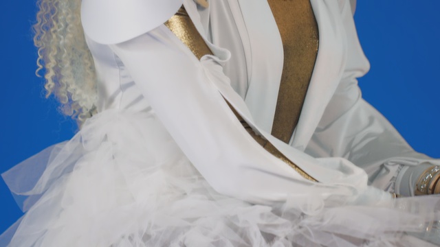 Video Reference: White, Dress, Wedding dress, Bridal clothing, Gown, Bridal accessory, Fashion accessory, Veil, Bride, Bed, Sitting, Woman, Table, Covered, Man, Laying, Wearing, Holding, Large, Blue, Ivory