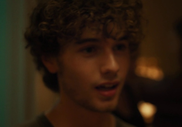 Video Reference: Face, Hair, Nose, Cheek, Portrait, Eyebrow, Forehead, Black, Facial expression, Lip, Person, Indoor, Looking, Holding, Young, Shirt, Front, Man, Wearing, Woman, Camera, Dark, Standing, Hand, Room, Glasses, Boy, Smiling, Suit, Red, White, Neck, Remote, Wall, Human face, Eyes, Screenshot, Chin