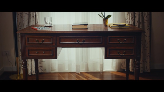Video Reference: furniture, desk, table, cabinetry, wood stain, hardwood, drawer, chest of drawers, sideboard, angle, Person