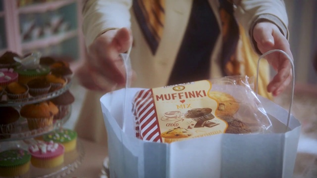 Video Reference: Food, Cuisine, Sweetness, Snack, Dish, Bake sale, Dessert, Baked goods, Pączki, Baking, Person, Table, Doughnut, Donut, Cup, Cake, Front, Woman, Holding, Sitting, Paper, Piece, Tray, Plate, Plastic, Eating, Close, Chocolate, Little, Bite, Glass, Young, Coffee, Sandwich, Standing, Man, White, Fast food, Human face