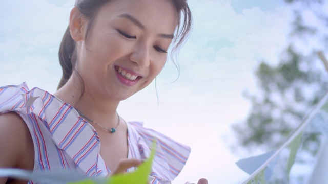 Video Reference: Facial expression, Skin, Smile, Nose, Beauty, Chin, Happy, Lip, Mouth, Fun, Person, Woman, Outdoor, Holding, Smiling, Looking, Lady, Girl, Front, White, Table, Young, Standing, Using, Phone, Food, Laptop, Man, Blue, Cutting, Cake, Pink, Fruit, Plate, Shirt, Umbrella, Sky, Human face, Fashion accessory, Clothing, Necklace