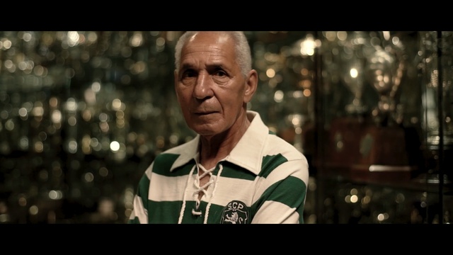 Video Reference: Human, Photography, Movie, Screenshot, Smile, Photo caption, Man, Person, Indoor, Standing, Front, Table, Holding, Glass, Wearing, Counter, Glasses, Uniform, Wine, Large, Kitchen, Silver, Display, White, Player, Shirt, Human face, Clothing, Portrait