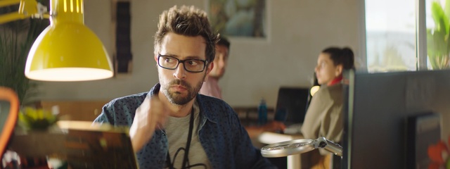 Video Reference: Eyewear, Glasses, Conversation, Room, Facial hair, Vision care, Beard, White-collar worker, Person, Indoor, Man, Table, Laptop, Sitting, Computer, Front, Looking, Food, Using, Woman, Desk, Young, Holding, Plate, People, Wall, Human face, Clothing, Human beard