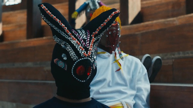 Video Reference: Ear, Design, Headgear, Mask, Textile, Pattern, Fashion accessory, Costume, Art, Person