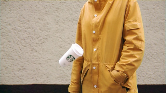 Video Reference: Clothing, Outerwear, Yellow, Overcoat, Sleeve, Jacket, Beige, Coat, Trench coat, Button, Person, Outdoor, Man, Standing, Holding, Wearing, Suit, Board, Woman, Walking, Carrying, Young, Street, Uniform, Hat, Talking, Shirt, Field, Beach, Riding, Snow, Phone, Ground, Collar, Human face, Trousers, Fashion accessory