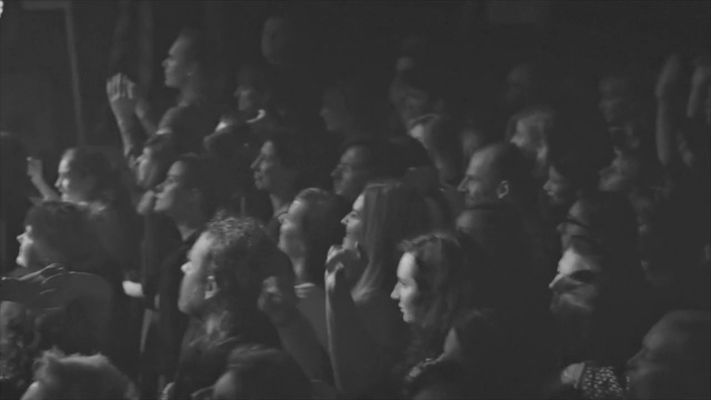Video Reference: Crowd, People, Black, Photograph, White, Audience, Monochrome, Black-and-white, Monochrome photography, Snapshot, Person, Photo, Standing, Dark, Woman, Holding, Group, Man, Sitting, Crowded, Room, Large, Street, Blurry, Pizza, Human face, Black and white