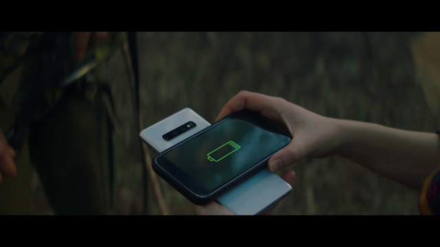 Video Reference: Gadget, Smartphone, Technology, Electronic device, Electronics, Finger, Hand, Communication device, Mobile phone, Portable communications device, Person, Cellphone, Phone, Holding, Woman, Using, Front, Small, Table, Computer, Laptop, Screen, Orange, Young, Keyboard, Man, Standing, Screenshot, Text, Telephone, Tablet computer