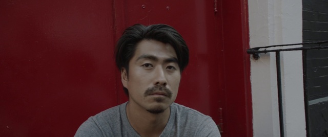 Video Reference: Hair, Face, Facial hair, Forehead, Chin, Cheek, Beard, Red, Eyebrow, Nose, Person, Man, Building, Indoor, Holding, Looking, Front, Shirt, Young, Camera, Sitting, Table, Posing, Using, Hand, Smiling, Wearing, Boy, Standing, Computer, Laptop, Woman, Mirror, Restaurant, White, Phone, Food, Sign, Room, Human face, Wall, Clothing, Portrait, Male