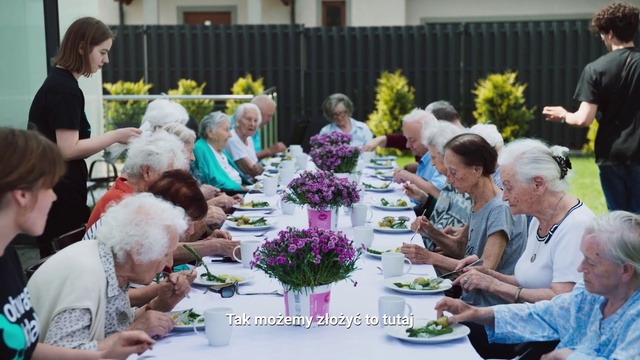 Video Reference: Meal, Event, Lunch, Community, Floristry, Rehearsal dinner, Flower arranging, Floral design, Party, Brunch, Person, Table, Indoor, Group, People, Sitting, Food, Cake, Plate, Woman, Birthday, Man, Eating, Dinner, Large, Older, Cutting, Young, White, Standing, Cut, Flower, Clothing, Family, Crowd