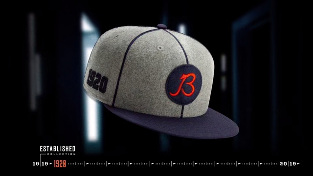 Video Reference: Cap, Clothing, Light, Baseball cap, Headgear, Line, Font, Fashion accessory, Hat, Logo, Indoor, Black, Sitting, Monitor, Red, Table, Computer, Small, Keyboard, Screen, Dark, Close, Orange, Desk, White, Bear, Game, Stuffed, Text, Ball, Sports equipment