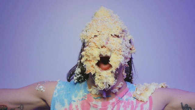 Video Reference: Frozen dessert, Dessert, Ice cream, Person, Cake, Food, Table, Sitting, Holding, Piece, Woman, Eating, White, Hand, Plate, Wedding, Red, Standing, Blue, Man, Flower, Baked goods