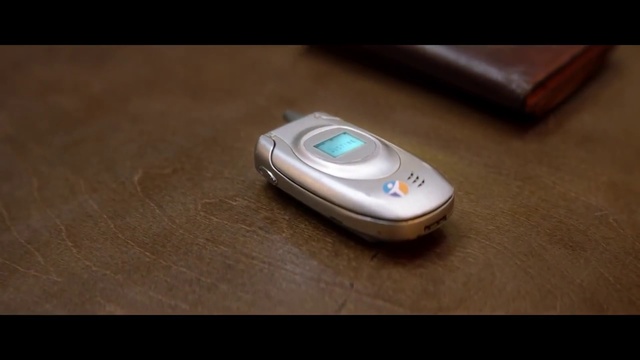 Video Reference: Product, Technology, Electronic device, Gadget, Indoor, Sitting, Table, Remote, Black, Wooden, Cellphone, Orange, Mouse, Laying, Desk, White, Blue, Mobile phone, Screenshot, Portable communications device, Telephone, Communication device, Smartphone