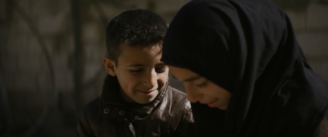 Video Reference: Child, Cheek, Human, Photography, Flash photography, Scene, Darkness, Smile, Black hair, Person, Man, Indoor, Young, Looking, Boy, Table, Sitting, Laptop, Holding, Standing, Food, Cutting, Computer, Cake, Black, Shirt, Eating, White, Board, Plate, People, Human face, Clothing, Portrait