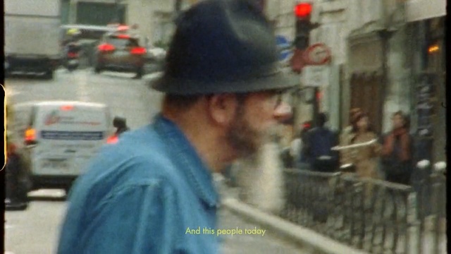 Video Reference: Pedestrian, Mode of transport, Street, Headgear, Photography, Vehicle, Automotive window part, Road, Glasses, Person