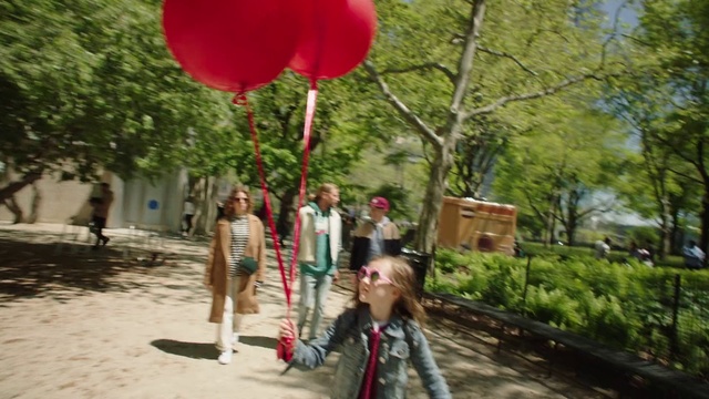 Video Reference: Balloon, Party supply, Fun, Tree, Leisure, Outdoor, Red, Walking, Carrying, Street, Holding, Riding, Man, Woman, Wearing, Snow, Water, Umbrella, Hat, Standing, Large, Track, Skiing, Ground, Clothing, Person, Girl