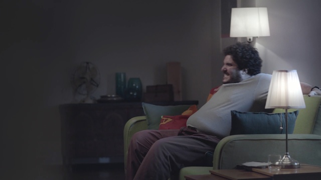 Video Reference: room, furniture, light, lamp, lighting, interior design, sitting, light fixture, table, darkness, Person