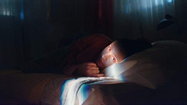 Video Reference: Light, Skin, Sleep, Child, Nap, Nose, Bed, Baby, Room, Bedtime, Indoor, Person, Sitting, Man, Looking, Laying, Lying, Laptop, Young, Girl, Little, Dark, Holding, Boy, Computer, Head, Woman, Large, Sleeping, White, Toddler, Human face, Clothing