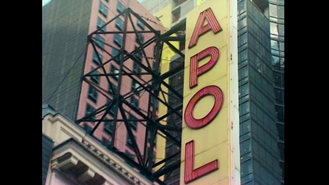 Video Reference: Architecture, Font, Landmark, Signage, Facade, Text, Snapshot, Electronic signage, Sign, Iron, Building, Outdoor, Large, Yellow, Clock, Side, Sitting, Front, Tall, Tower, Red, Hanging, Light, Traffic, City, Glass, Black, Street, Store, White, Standing, Window, Sky