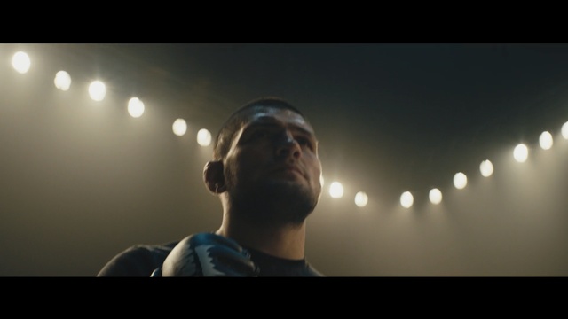 Video Reference: Backlighting, Light, Lens flare, Lighting, Photography, Audio equipment, Sky, Performance, Microphone, Music, Person, Man, Indoor, Object, Looking, Photo, Front, Computer, Holding, Laptop, Screen, Wearing, Dark, Sitting, Using, Room, Standing, Phone, Monitor, Woman, Mirror, Table, Video, Young, Hat, Remote, Playing, Human face, Screenshot