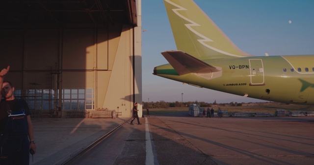 Video Reference: Airline, Air travel, Airplane, Aerospace engineering, Aviation, Vehicle, Aircraft, Sky, Mode of transport, Airport, Outdoor, Plane, Road, Sitting, Large, Air, Runway, Parked, Jet, Yellow, Tarmac, Green, White, Aerospace manufacturer
