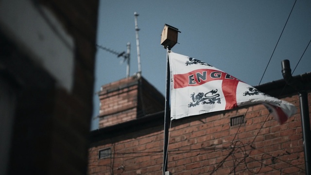 Video Reference: Flag, Wall, Urban area, Banner, Sky, Architecture, Font, Advertising, Brick, Signage