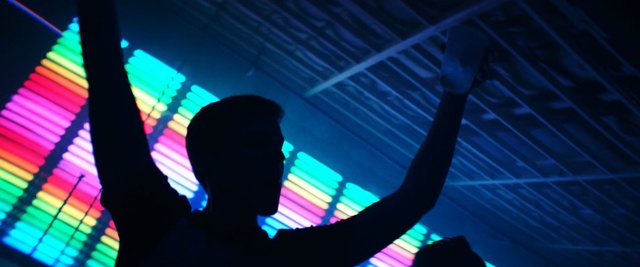 Video Reference: Blue, Light, Visual effect lighting, Line, Electric blue, Neon, Television, Sitting, Striped, Man, Dark, Screen, Monitor, Zebra, Lit, Holding, Woman, Colorful, Standing, Street, Room, Blurry, Playing, Concert, Person, Music