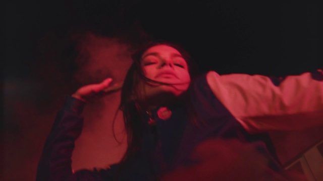 Video Reference: Red, Performance, Fun, Human body, Mouth, Event, Adaptation, Darkness, Room, Stage, Person, Dark, Indoor, Man, Lit, Looking, Light, Holding, Woman, Laptop, Night, Bed, Sitting, Front, Wearing, Young, Standing, Black, Computer, Screen, Shirt, Playing, Phone, Cat, Video, Game, Remote, Blurry, White, Human face, Concert, Clothing