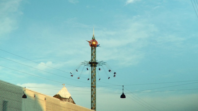 Video Reference: Sky, Blue, Cloud, Pole, Steeple, Technology, Tower, Light fixture, Street light, Electricity, Person, Outdoor, Street, Ship, Light, Boat, Snow, Traffic, Water, View, Truck, Skiing, Large, Hanging, Red, Intersection, City, White, Sign, People, Group, Man, Standing, Track, Parked, Train, Riding, Day