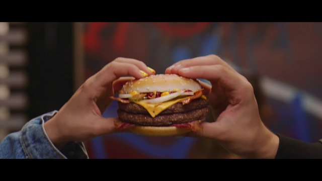 Video Reference: Junk food, Food, Fast food, Hamburger, Cheeseburger, Cuisine, Dish, Buffalo burger, Bacon sandwich, Breakfast sandwich, Person, Indoor, Sandwich, Table, Eating, Sitting, Holding, Piece, Hand, Small, Close, Plate, Woman, Hot, Man, Baked goods, French fries, Slider, Hot dog, Crab, Patty, Veggie burger, American food, Banh ma, Bun, Breakfast roll, Cemita, Snack food